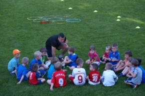 Trener objaśnia młodszej grupie piłkarzy zasady następnej zabawy