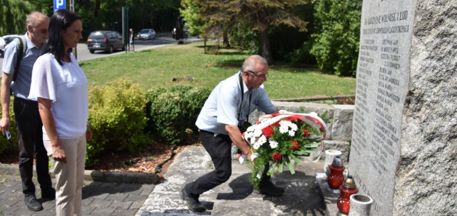 Składnie kwiatów pod pomnikiem znajdującym się przed wejściem do urzędu